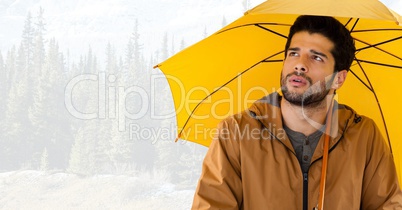 Man with yellow umbrella in bright forest
