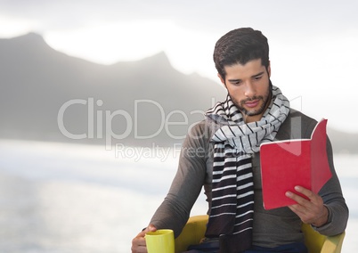 Man reading with cup by sea mountains