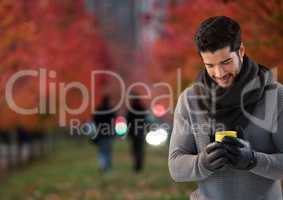 Man in Autumn with phone in city park