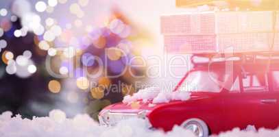 Toy car carrying christmas present on fake snow