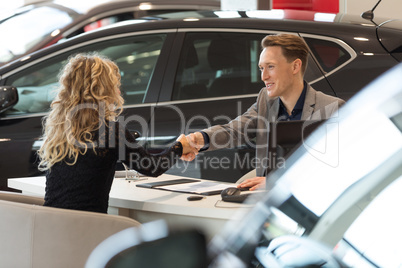 Smiling salesman doing handshake with female customer