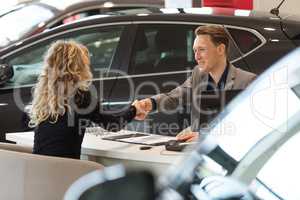Smiling salesman doing handshake with female customer