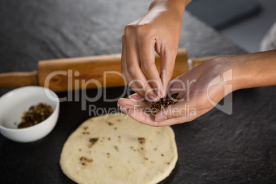 Woman adding dry fruits over flattened dough