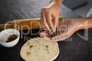 Woman adding dry fruits over flattened dough