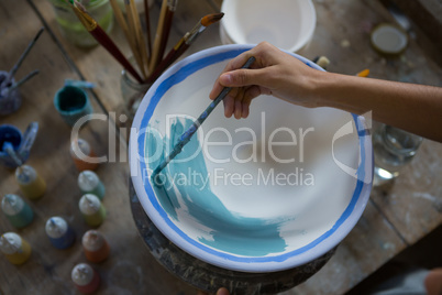 Female potter hand painting a bowl