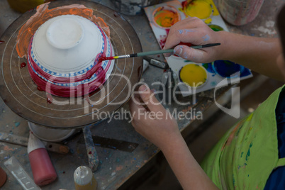 Boy painting a bowl in pottery shop