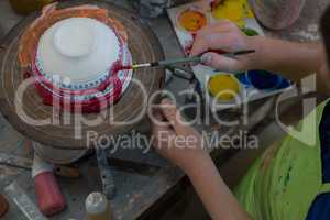 Boy painting a bowl in pottery shop