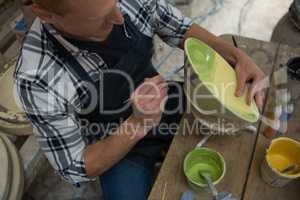 Male potters hand painting a bowl
