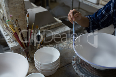 Female potter painting a bowl Female potter painting a bowl