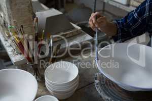 Female potter painting a bowl