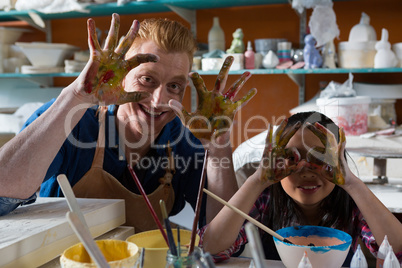 Male potter and girl showing their painted hands