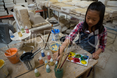 Attentive girl painting bowl