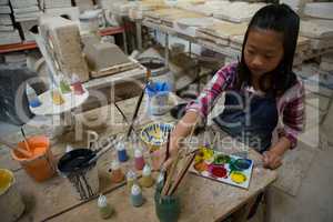 Attentive girl painting bowl