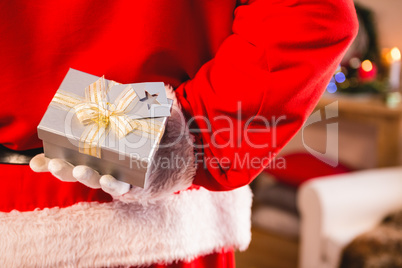 Santa claus hiding a gift box behind his back