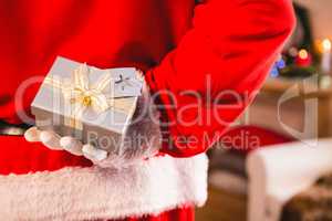 Santa claus hiding a gift box behind his back