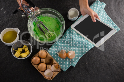 Woman using a tablet phone after preparing batter