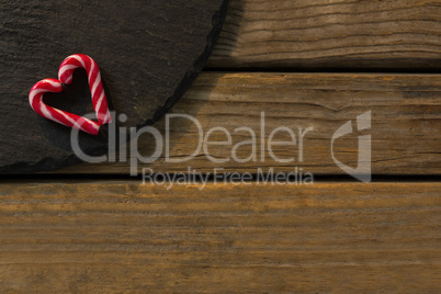 View of candy cane arranged in heart shape on wood
