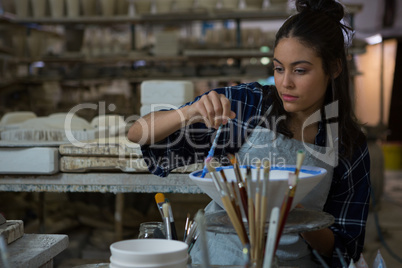 Female potter painting a bowl