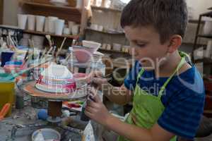 Boy painting a bowl in pottery shop