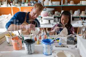 Male potter and girl painting bowl