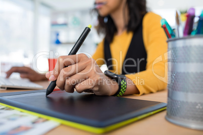 Female executive working over graphic tablet at her desk