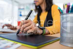 Female executive working over graphic tablet at her desk