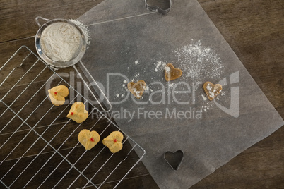 Sieve with icing sugar cookies on cooling rack