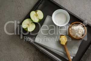 Bowl of sugar and apple, flour with butter in spoon