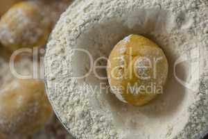 Dough ball placed over flour on a wooden table