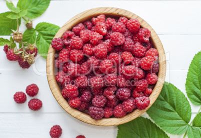 ripe red raspberries in a wooden bowl