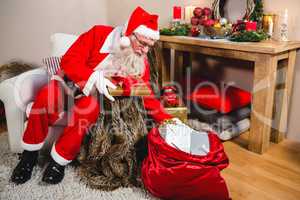 Santa claus removing gift from gift sack in living room at home