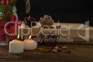 Close up of illuminated candles with pine cones and gift box