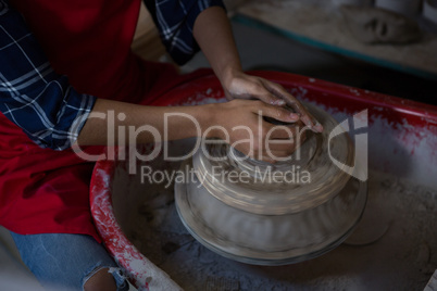 Mid section of female potter molding a clay