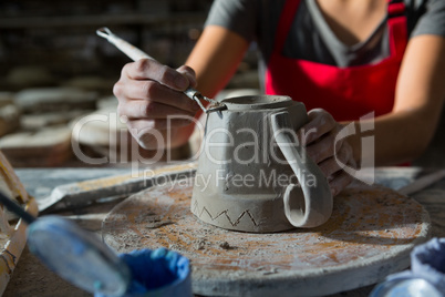 Female potter carving mug