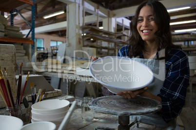 Portrait of female potter painting bowl