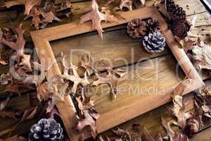 Frame and dry leaves on wooden plank