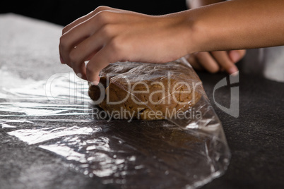 Woman wrapping dough in a plastic wrap