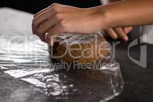 Woman wrapping dough in a plastic wrap