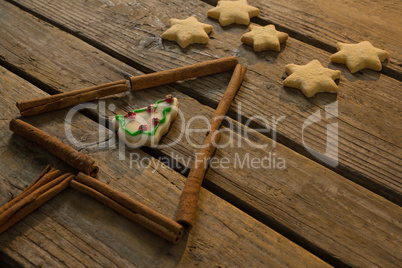 Close up of star shape cookies by Christmas tree made with cinnamon stick
