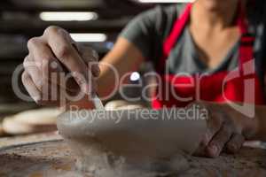 Female potter molding a bowl with hand tool