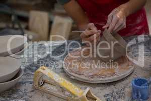 Female potter carving mug