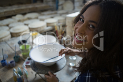 Portrait of female potter painting bowl