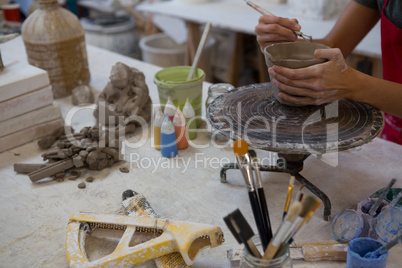 Female potter molding a mug with hand tool