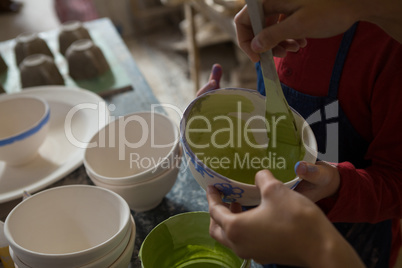 Mid section of female potter and boy painting bowl