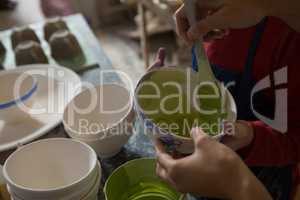 Mid section of female potter and boy painting bowl