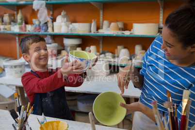 Female potter and boy painting bowl