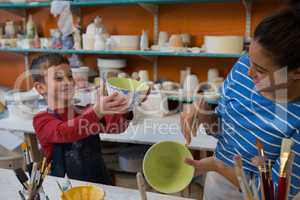 Female potter and boy painting bowl