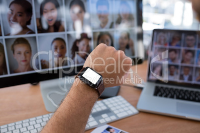 Male executive checking time on smartwatch at desk