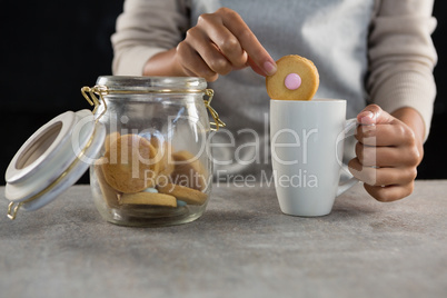 Woman dipping a cookie into a mug