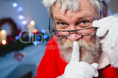 Santa claus keeping his finger on lips at home